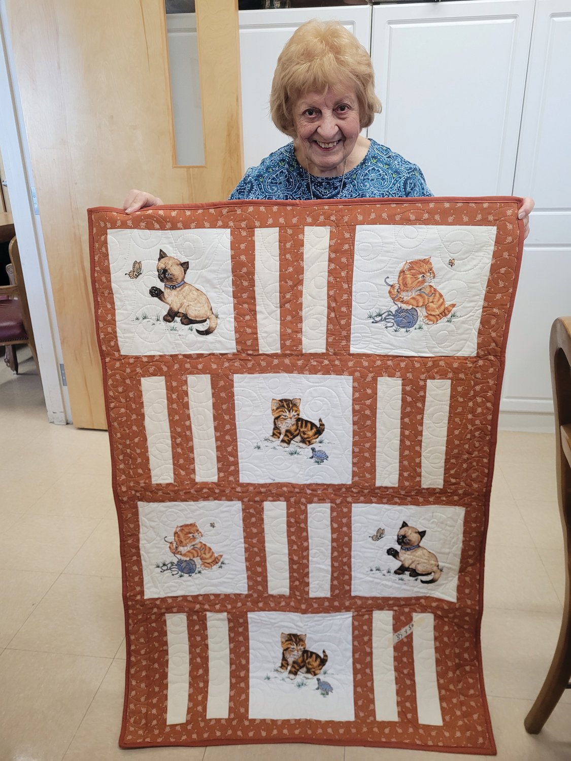 FELINE FRIENDS: Marie Lanzi unfurled one of her favorite recent quilting master patchworks. The quilt was one of more than 50 donated to community service organization Children’s Friend and Services.